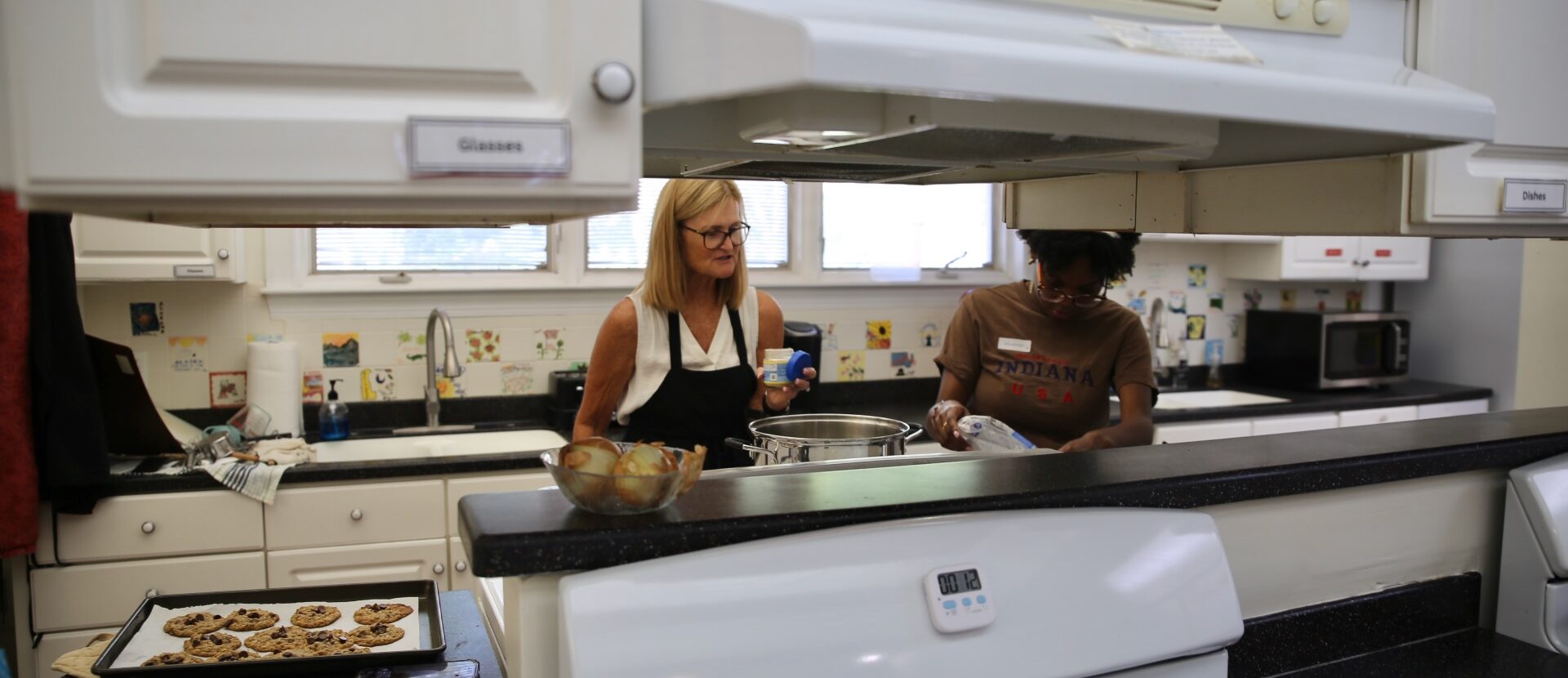 Two women work in a kitchen baking cookies.