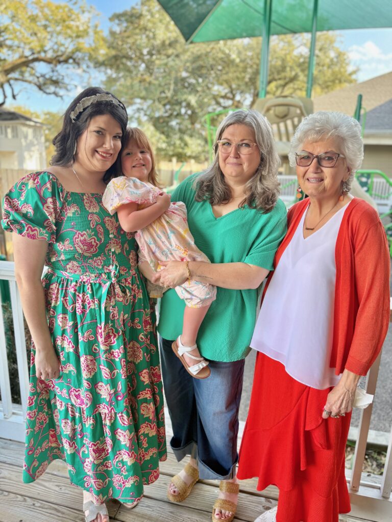 An older Bristol with her family smiling at the camera outside.