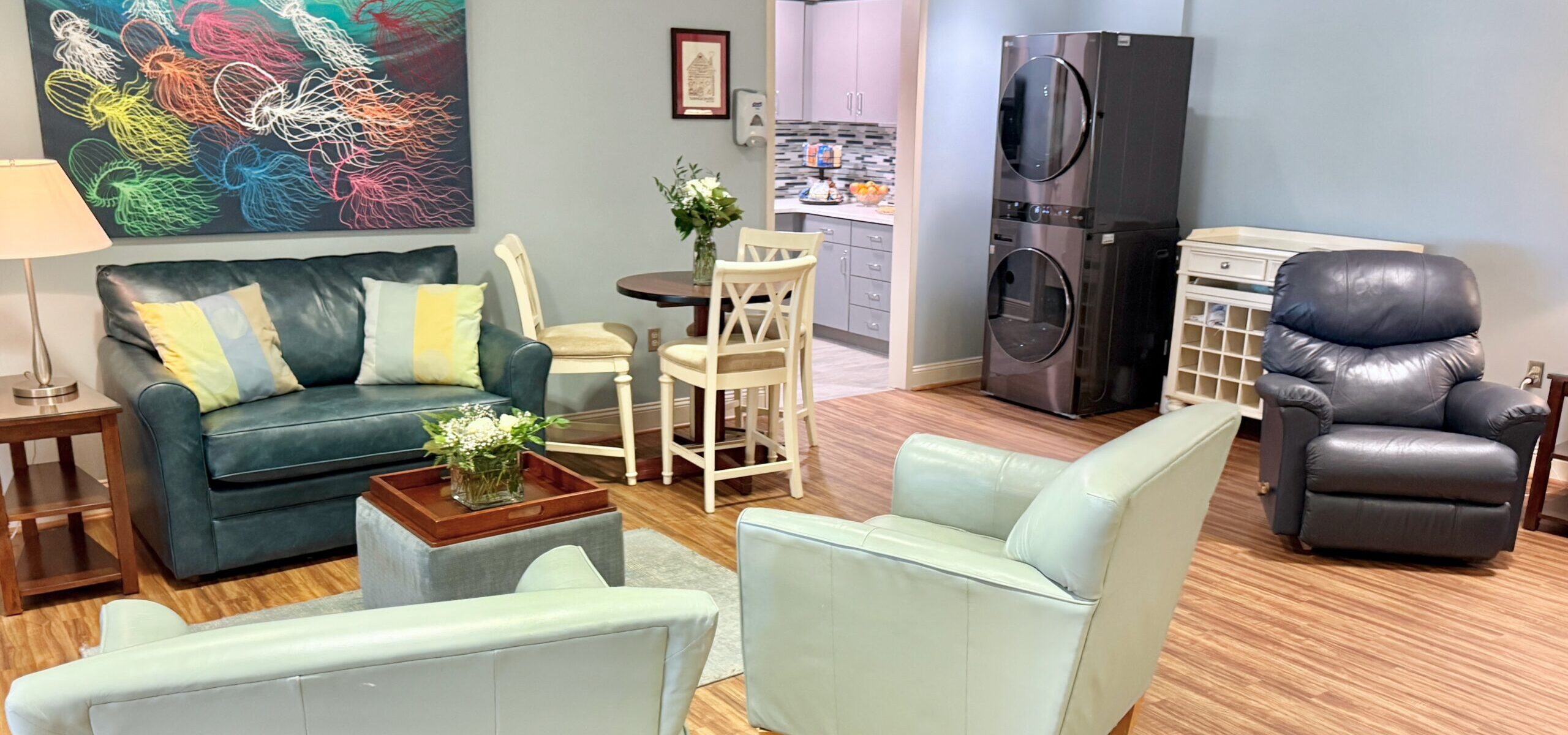 View of the Family Room showing comfortable seating, kitchen, and washer dryer.