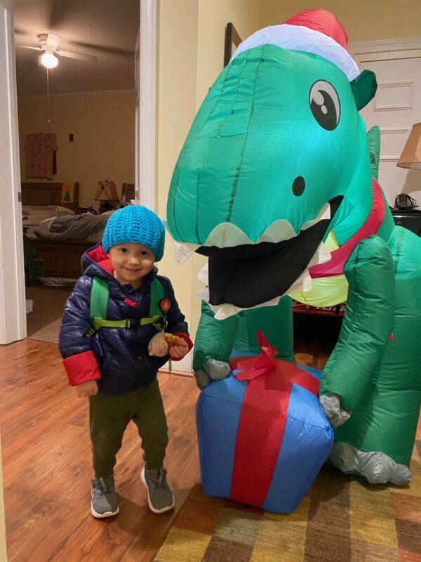 Claud poses with an adult in a blow-up dinosaur costume.